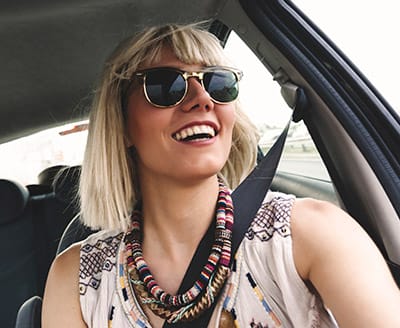 A young woman wearing sunglasses sitting in a car.