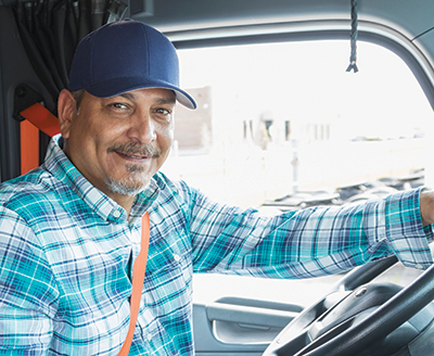 A man smiling and wearing a hat sitting in a truck.
