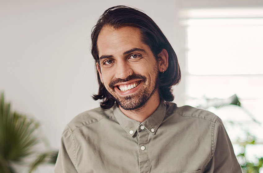 Headshot of future staff member, a man wearing a tan shirt in an office.